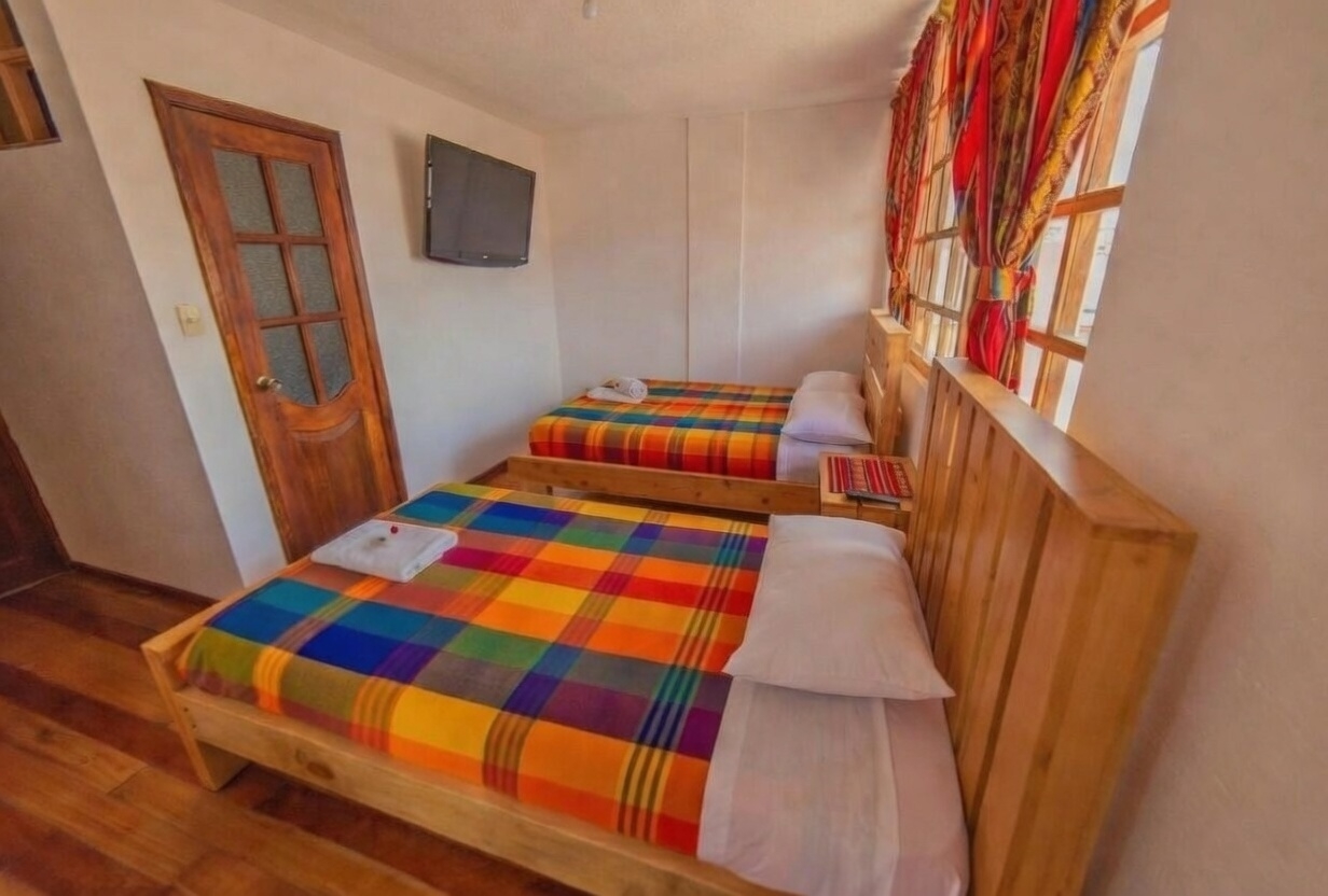 Habitación triple espaciosa con escritorio y sofá en Hotel El Andariego Otavalo
